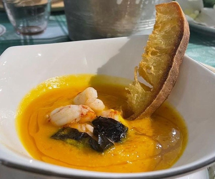Vellutata arancione con gamberi, verdure scure, filo d'olio e pane tostato in fondina bianca, Armonie di Paola